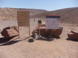 A map and sign on the edge of the parking lot, and also a small dog called Xuxa looking for some shade