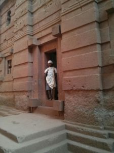 A monk standing in the door of Biete Amanuel Church - Monolithic Churches