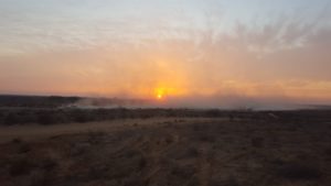 The cloud of dust and podwer the tank raise with the sunset on the background