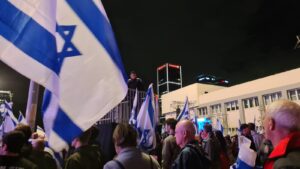 A policeman standing on a stage above the protest - 11th week