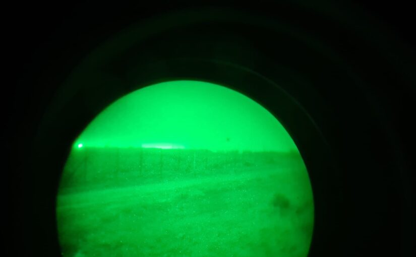Looking on the border fence through a night vision decice - defense fighting
