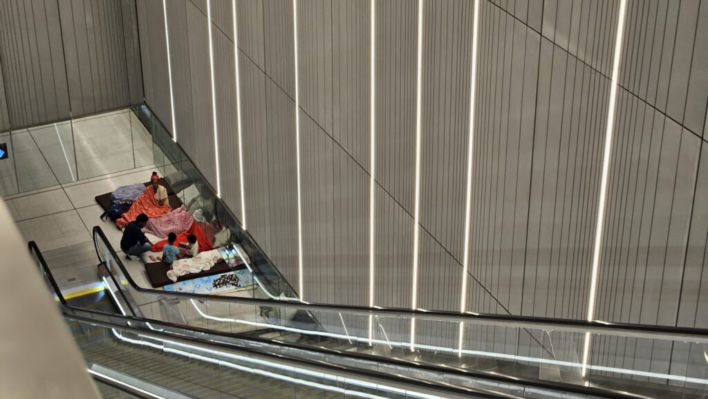 Sleeping down on the trains level of the station along the platform. - shelter stations