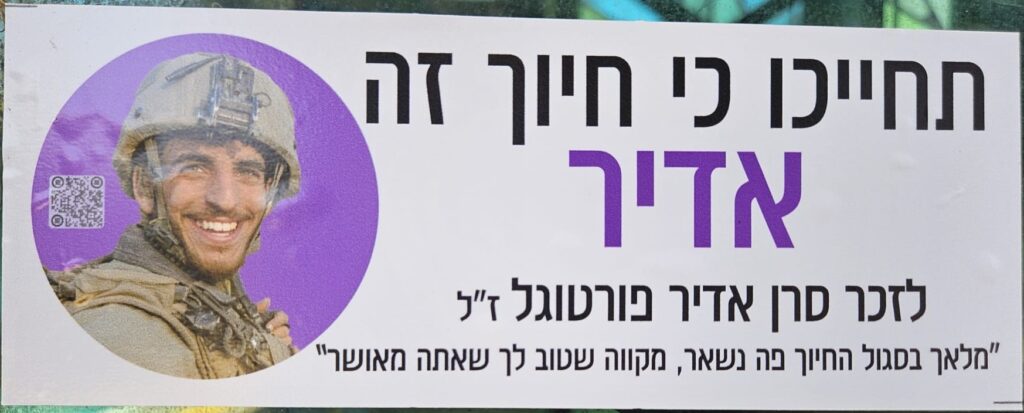 תחייכו כי חיוך אדיר לזכר סרן אדיר פורטוגל ז"ל "מלאך בסגול החיוך פה נשאר, מקווה שטוב לך שאתה מאושר" Smile, because a smile is Adir (mighty) In memory of Captain Adir Portugal, of blessed memory "An angel in purple — the smile remains here, hoping you're well, that you're happy"