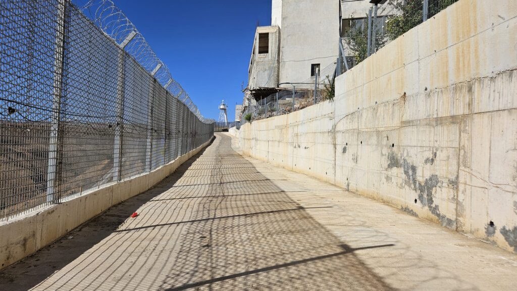 The road above the Hasbani north of the walkway, it is mostly a security road and not nice to walk - Fence on side and a concrete wall on the other