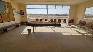 A cabin with the map of the United Nations Partition Plan for Palestine and map of the Peel Commission as well as a table with the water system built here.