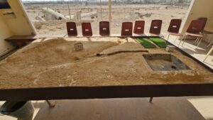 A cabin with the map of the United Nations Partition Plan for Palestine and map of the Peel Commission as well as a table with the water system built here.