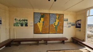 A cabin with the map of the United Nations Partition Plan for Palestine and map of the Peel Commission as well as a table with the water system built here.