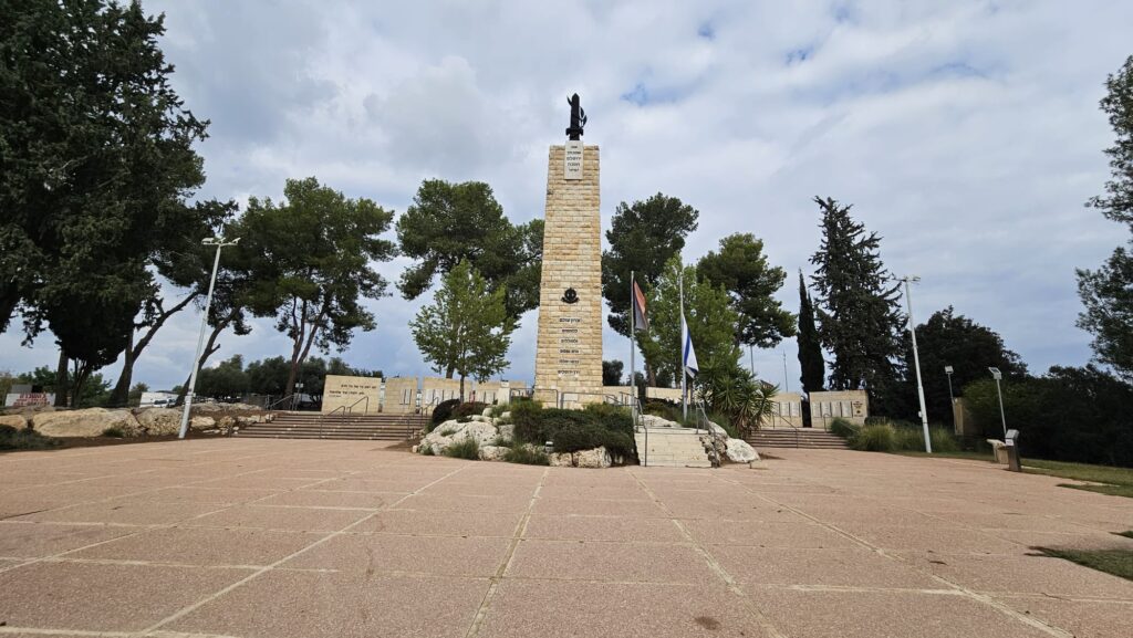 The "Road of Heroism" monument in the middle of the square, and the walls with the names of the fallen in the back.